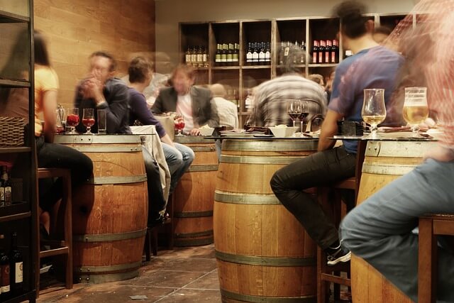 Una imagen que muestra un bar de vinos con una variada selección de vinos expuestos, incluidos barriles de vino reutilizados creativamente como mesas, creando un ambiente único y rústico para disfrute de los entusiastas del vino.